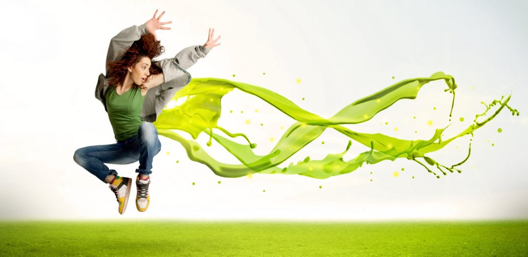 Pretty girl jumping with green abstract liquid dress concept in nature